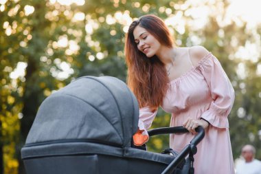 Aile, çocuk ve ebeveyn kavramı - mutlu anne ile bebek arabası Park yürüme.