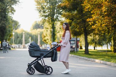 Aile, çocuk ve ebeveyn kavramı - mutlu anne ile bebek arabası Park yürüme.