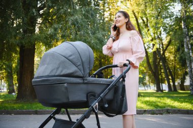 mutlu genç anne ile bebek arabası sonbahar parkta yürüyüş