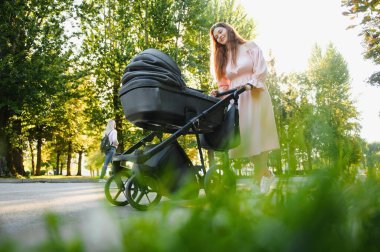 Annem caddede yürüyor. Bebek arabasında oturan bir kadın bebeğini itiyor. Aile kavramı.
