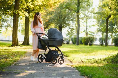 Aile, çocuk ve ebeveyn kavramı - mutlu anne ile bebek arabası Park yürüme.