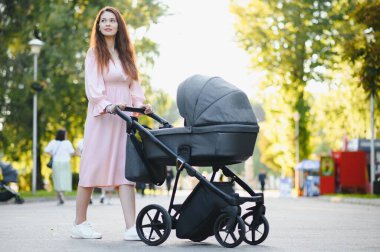 mutlu genç anne ile bebek arabası sonbahar parkta yürüyüş