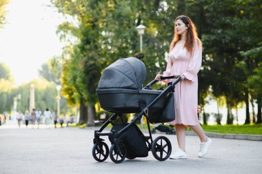 Annem caddede yürüyor. Bebek arabasında oturan bir kadın bebeğini itiyor. Aile kavramı.