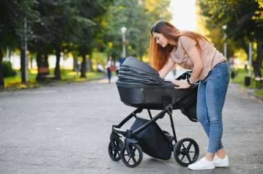 Aile, çocuk ve ebeveyn kavramı - mutlu anne ile bebek arabası Park yürüme.