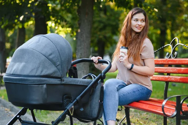 Glückliche Junge Mutter Mit Baby Buggy Sitzt Auf Bank Herbstpark — Stockfoto