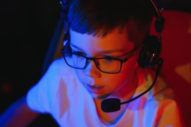 Küçük çocuk karanlık odada video oyunu oynuyor.