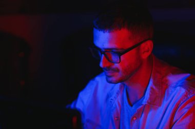 Profesyonel Oyuncu. Millennial Guy, evde oturup online video oyunu oynayan masaüstü bilgisayarını kullanıyor. Neon Işıkları, Seçici Odaklanma