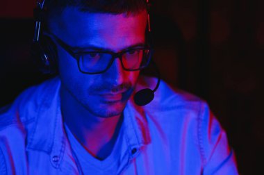 Profesyonel Oyuncu. Millennial Guy, evde oturup online video oyunu oynayan masaüstü bilgisayarını kullanıyor. Neon Işıkları, Seçici Odaklanma