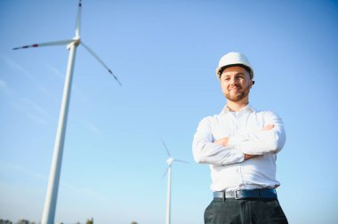 Makinist ayakta duruyor ve rüzgar türbiniyle dizüstü bilgisayar yüklüyor..