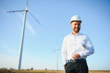 Mühendisler yakışıklı bir gülümsemeyle türbinin önüne bakıyor.