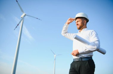 Mühendisler yakışıklı bir gülümsemeyle türbinin önüne bakıyor.