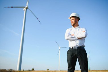 Mühendisler yakışıklı bir gülümsemeyle türbinin önüne bakıyor.