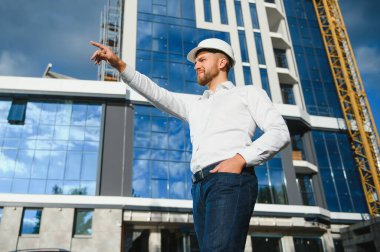 İnşaat işçisi inşaat alanındaki beton pompayı ve günbatımını kontrol ediyor.