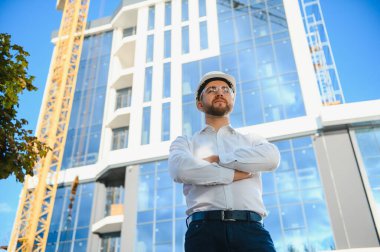 İnşaat işçisi inşaat alanındaki beton pompayı ve günbatımını kontrol ediyor.