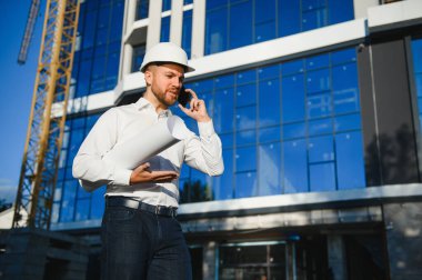 Yeni binanın yanındaki miğferli mimar