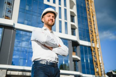 İnşaat alanındaki çatı yapıları ve günbatımı arka planında bir inşaat işçisi kontrolü