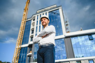 İnşaat alanındaki çatı yapıları ve günbatımı arka planında bir inşaat işçisi kontrolü