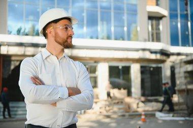 Başarılı mühendis ya da mimar, vinç ve bina inşaatı. Miğfer takan neşeli iş adamı.