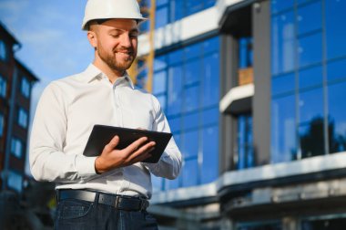 Başarılı mühendis ya da mimar, vinç ve bina inşaatı. Miğfer takan neşeli iş adamı.