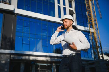 Başarılı mühendis ya da mimar, vinç ve bina inşaatı. Miğfer takan neşeli iş adamı.