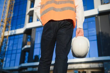 El mühendisi, arka planda bina olan kaskı tutuyor..