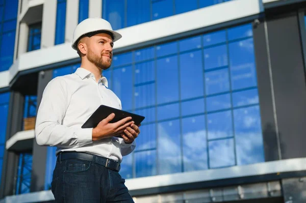 Construction engineer with the tablet pictures of objects on a construction site