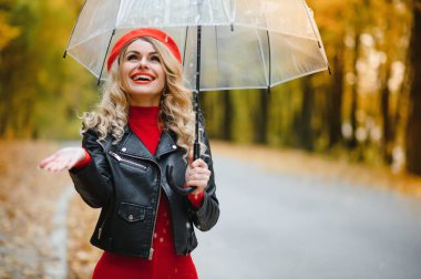 Şemsiye altındaki kadın sonbaharda parkta yürür.