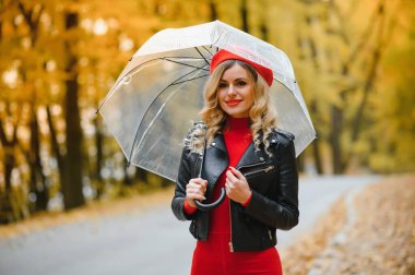 Sonbahar parkta bir şemsiye altında bir kız yürüyor
