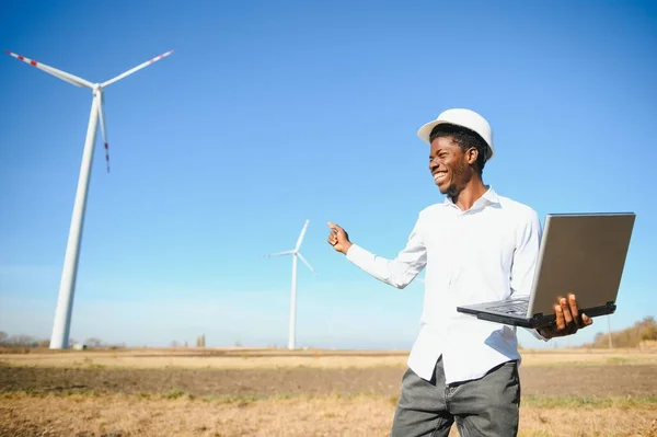 Afrikanischer Ingenieur Steht Und Hortet Laptop Mit Windkraftanlage — Stockfoto