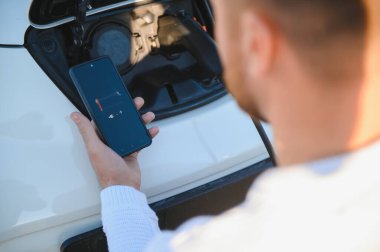 Adam şarj istasyonunda bir elektrikli arabayı şarj ediyor.