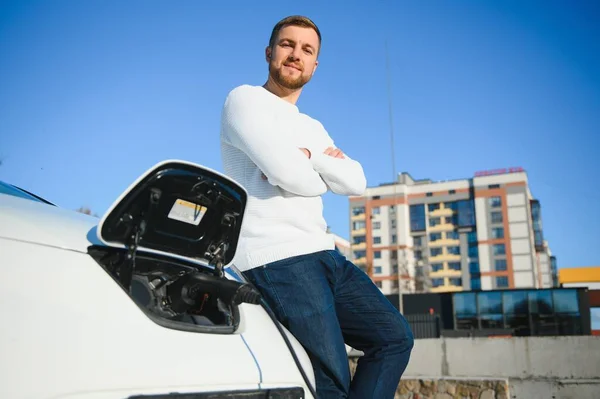 Junger Hübscher Mann Hält Ladekabel Stromtankstelle Der Nähe Seines Neuen — Stockfoto