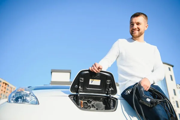 Junger Hübscher Mann Hält Ladekabel Stromtankstelle Der Nähe Seines Neuen — Stockfoto