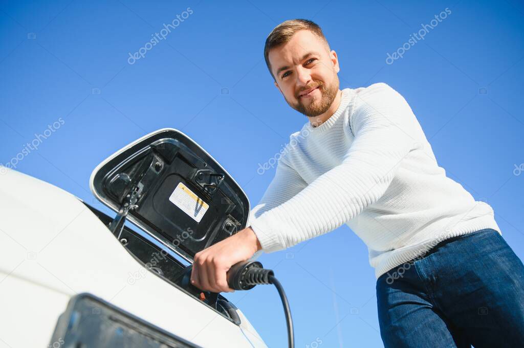 Smiling man unplugging the charger from the car