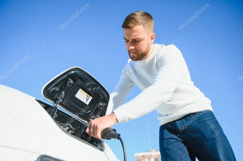 Smiling man unplugging the charger from the car