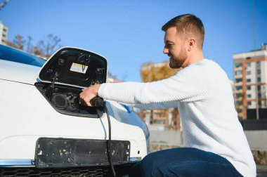 Gülümseyen adam araba şarj cihazını prizden