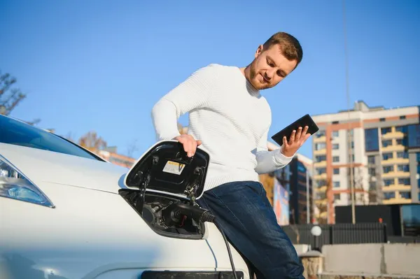 Genç Yakışıklı Adam Elektrik Şarj Istasyonunda Kablo Tutuyor Yeni Arabasının — Stok fotoğraf