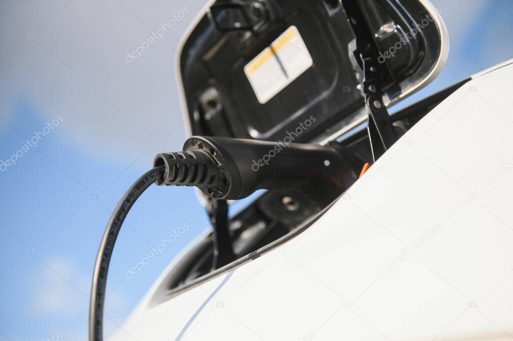 Charging modern electric car battery on the street which are the future of the Automobile, Close up of power supply plugged into an electric car being charged for hybrid . New era of vehicle fuel.