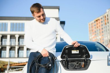 Gülümseyen adam araba şarj cihazını prizden