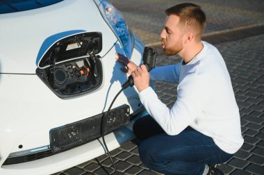 Gülümseyen adam araba şarj cihazını prizden