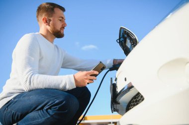 Gülümseyen adam araba şarj cihazını prizden