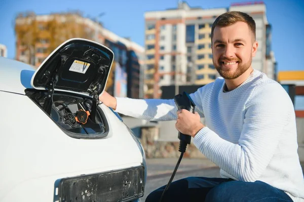 Junger Hübscher Mann Hält Ladekabel Stromtankstelle Der Nähe Seines Neuen — Stockfoto