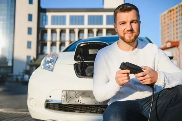 笑みを浮かべて男の車から充電器を抜く — ストック写真