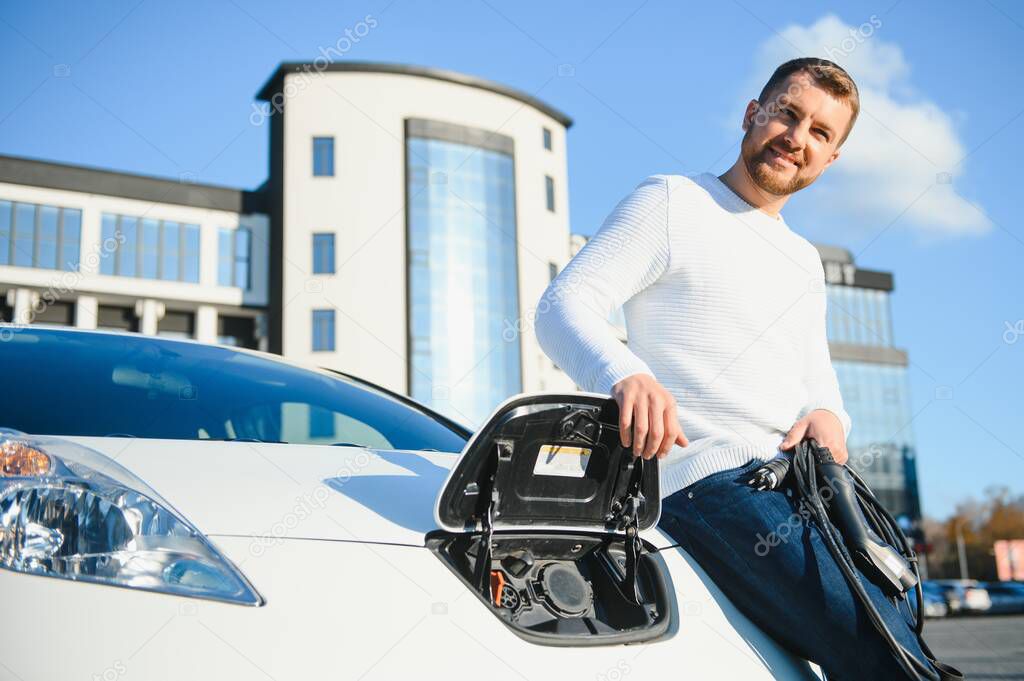 Man charges an electric car at the charging station