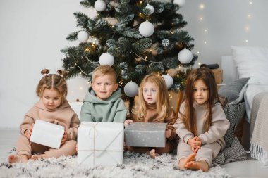 Evdeki Noel ağacının altında bir grup çocuk. Süslü kostümlü kızlar ve erkekler kış tatilini kutluyor. Çocuklar şöminenin yanındaki hediyeleri açın..