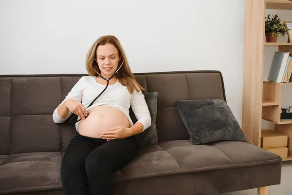 Wanita Hamil Menggunakan Stetoskop Memeriksa Perutnya Sofa Happy Wanita Hamil — Stok Foto