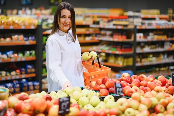 Sebze rafındaki süpermarkette alışveriş yapan bir kadın...