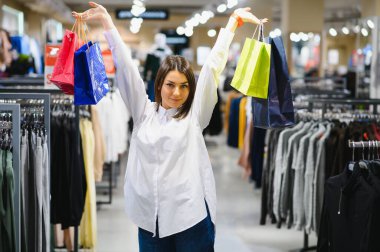 Alışveriş yapan bir kadın. Alışveriş torbalarıyla alışveriş yapan mutlu bir kadın. Tüketim, alışveriş, yaşam tarzı konsepti