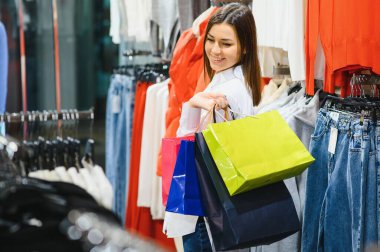 Alışveriş yapan bir kadın. Alışveriş torbalarıyla alışveriş yapan mutlu bir kadın. Tüketim, alışveriş, yaşam tarzı konsepti