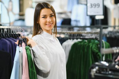 Galeride elbise seçen genç bir kadın.