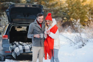 Tatlı bir çift, Kış Ormanı pikniğinde çay içiyorlar. Doğa pikniği. Arabadaki Aşk Hikayesi.